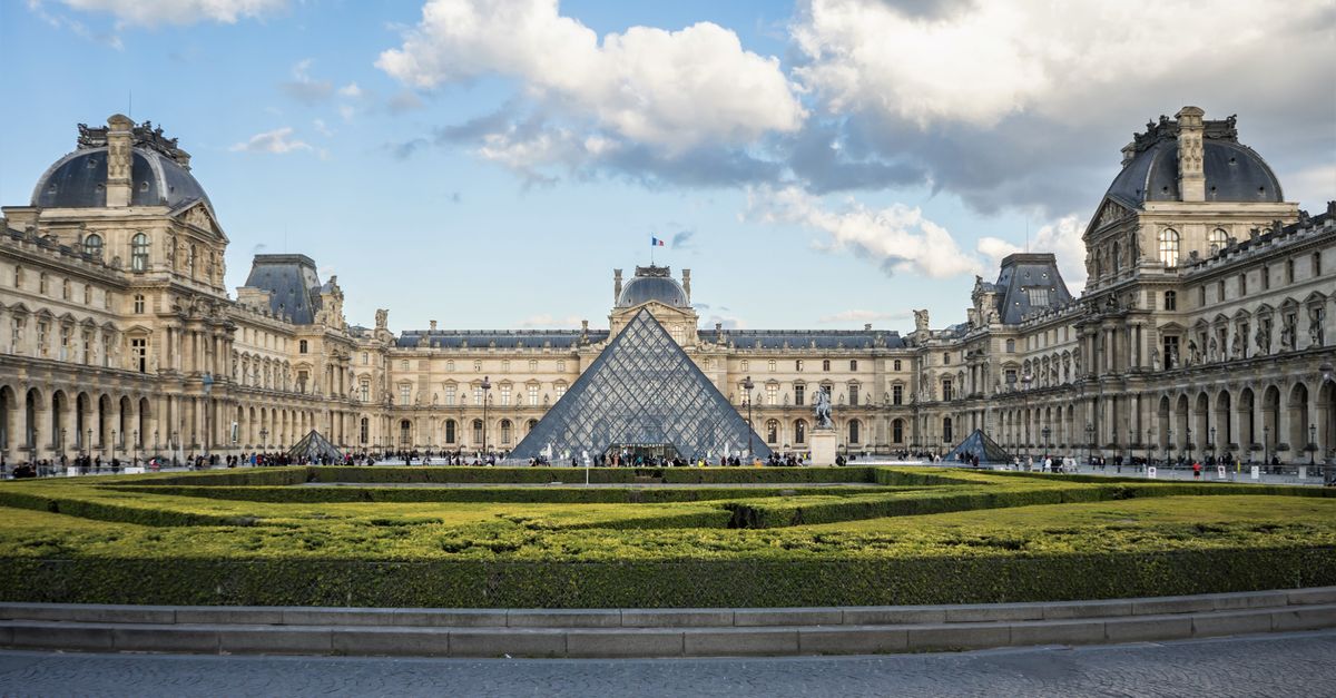 The Louvre Museum with its iconic glass pyramid in Paris, France.